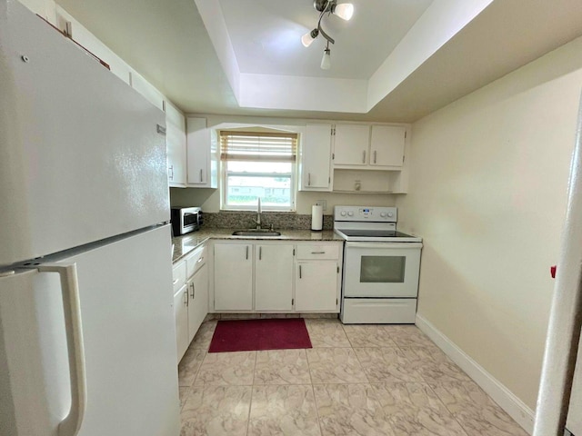 kitchen featuring white appliances, a raised ceiling, white cabinetry, and sink