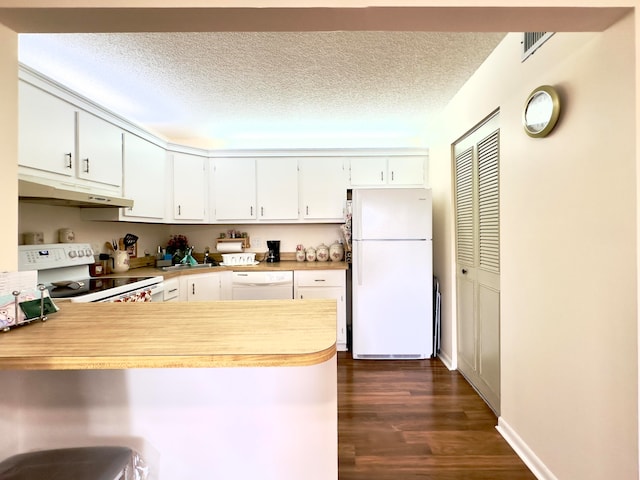 kitchen featuring white cabinets, sink, kitchen peninsula, white appliances, and dark hardwood / wood-style floors