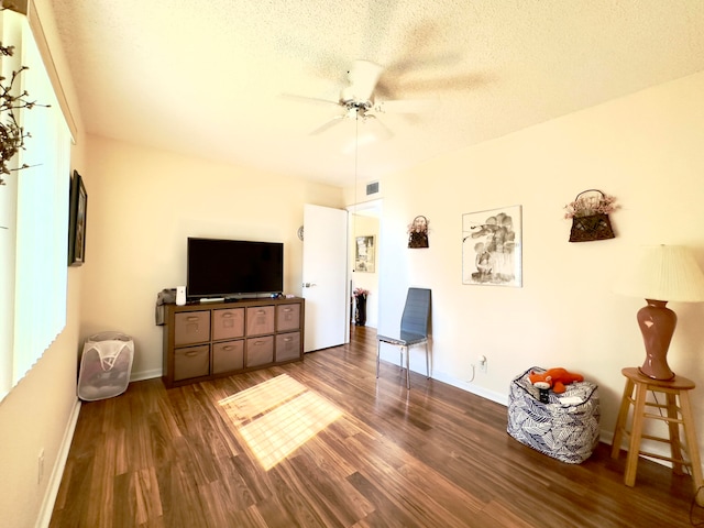 living room with ceiling fan, dark hardwood / wood-style floors, and a textured ceiling