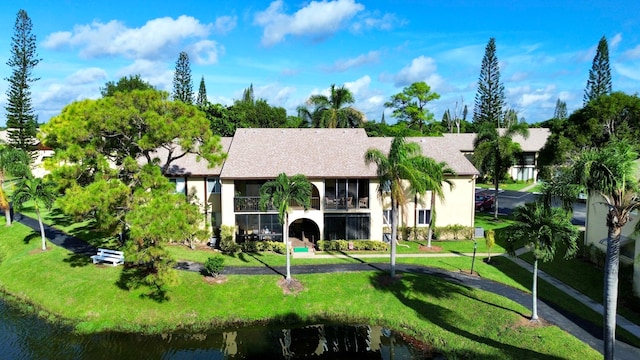 rear view of house featuring a lawn, a water view, and a balcony