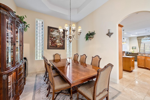 dining space with a raised ceiling and a chandelier