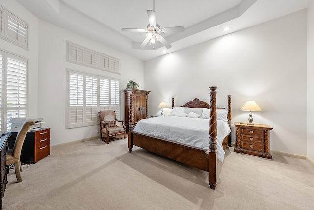 carpeted bedroom featuring ceiling fan, a tray ceiling, a towering ceiling, and multiple windows