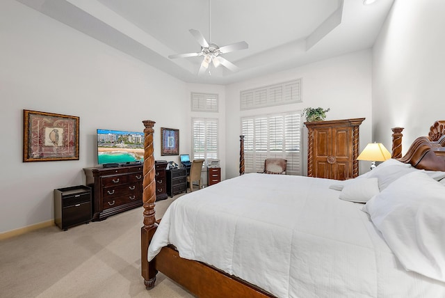 bedroom featuring a raised ceiling, a high ceiling, ceiling fan, and light colored carpet