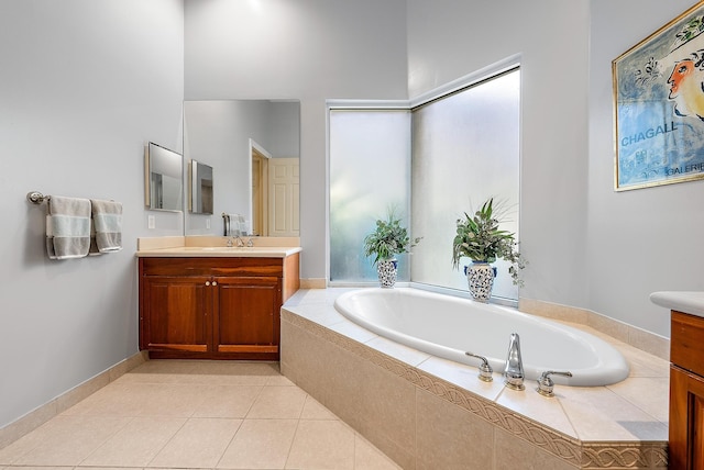 bathroom with a relaxing tiled tub, vanity, and tile patterned flooring