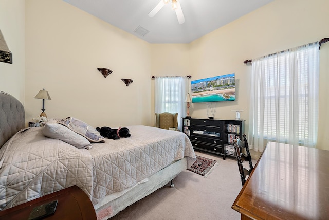 bedroom featuring ceiling fan, light colored carpet, and multiple windows