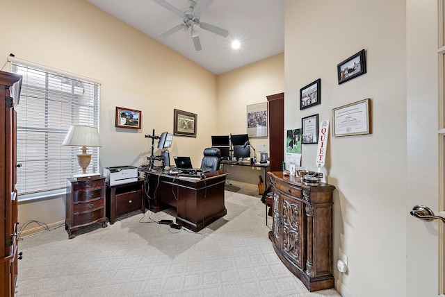 office featuring ceiling fan, light carpet, and a towering ceiling