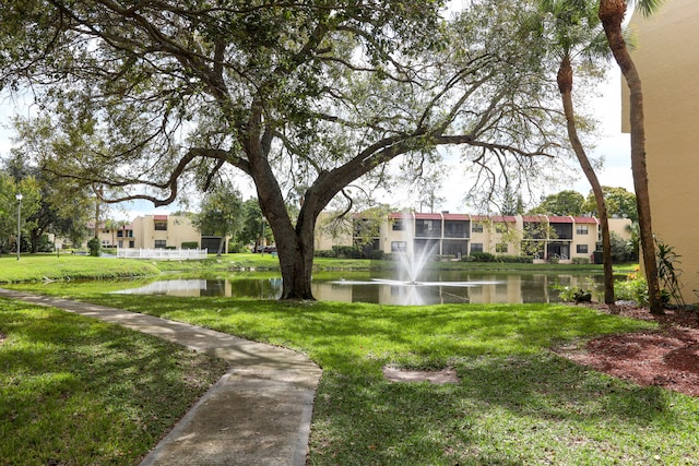 view of home's community with a water view and a lawn
