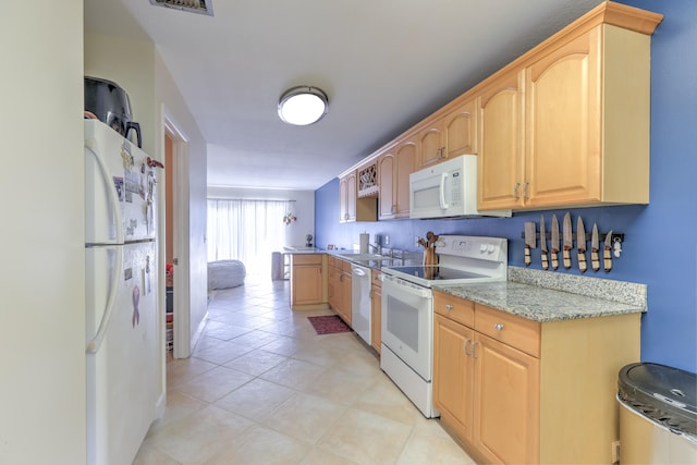 kitchen with a sink, light brown cabinets, light tile patterned flooring, light stone countertops, and white appliances