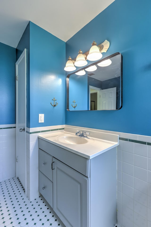 bathroom with tile walls, a wainscoted wall, and vanity