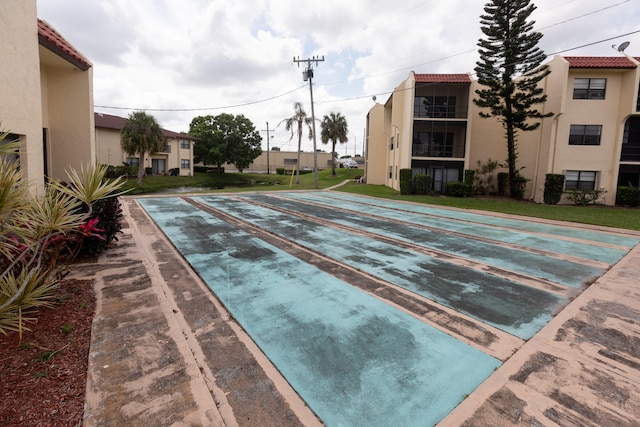 view of property's community with uncovered parking and shuffleboard