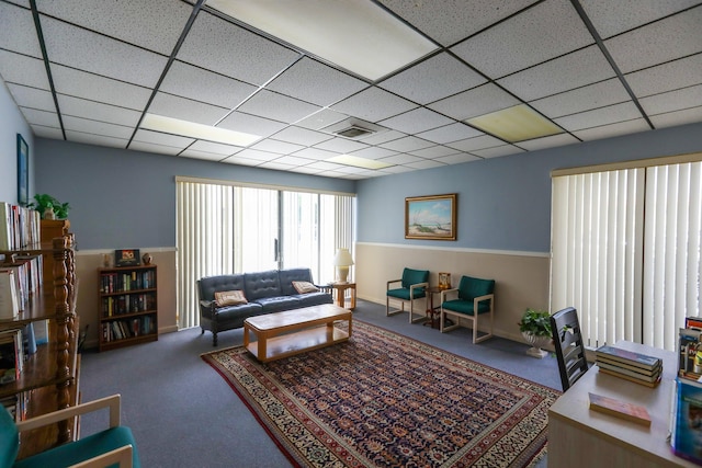 living room featuring a paneled ceiling, visible vents, carpet floors, and baseboards