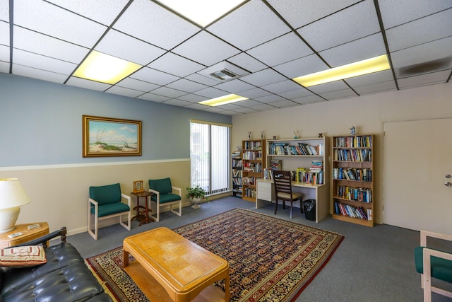 sitting room with a drop ceiling, visible vents, and carpet floors