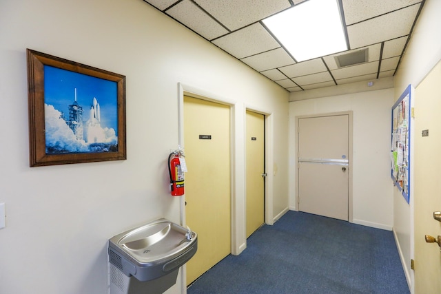 hallway featuring a drop ceiling, visible vents, and carpet floors