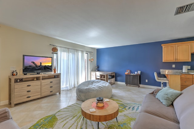 living room featuring light tile patterned floors, visible vents, and baseboards