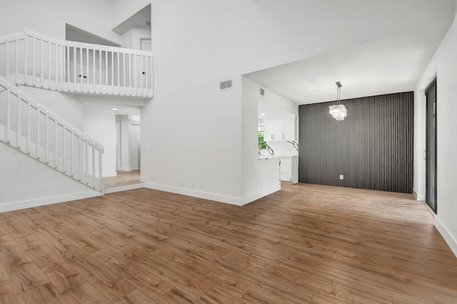 unfurnished living room with a chandelier, hardwood / wood-style flooring, and a high ceiling