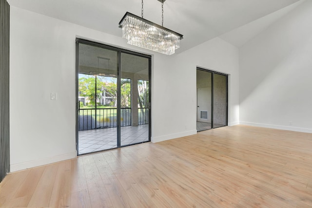 unfurnished room with vaulted ceiling, a notable chandelier, and light hardwood / wood-style floors