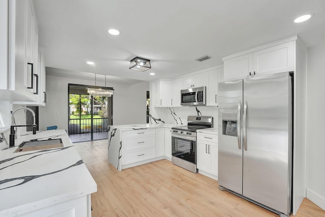 kitchen featuring stainless steel appliances, white cabinetry, sink, and light wood-type flooring