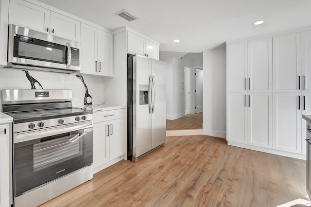 kitchen with light wood-type flooring, white cabinets, and stainless steel appliances