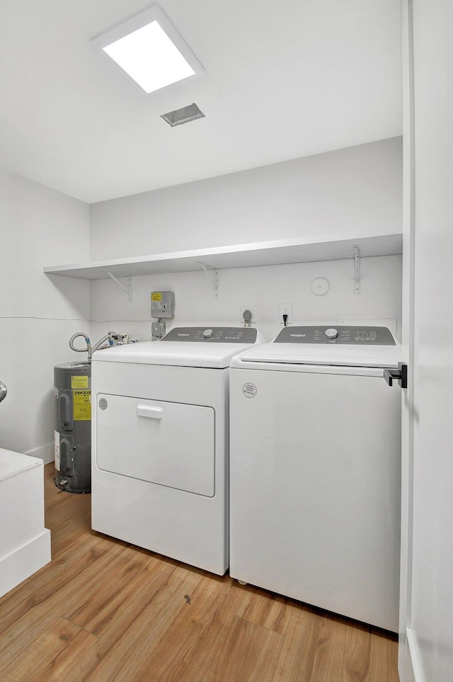 washroom featuring electric water heater, light hardwood / wood-style floors, and washing machine and dryer