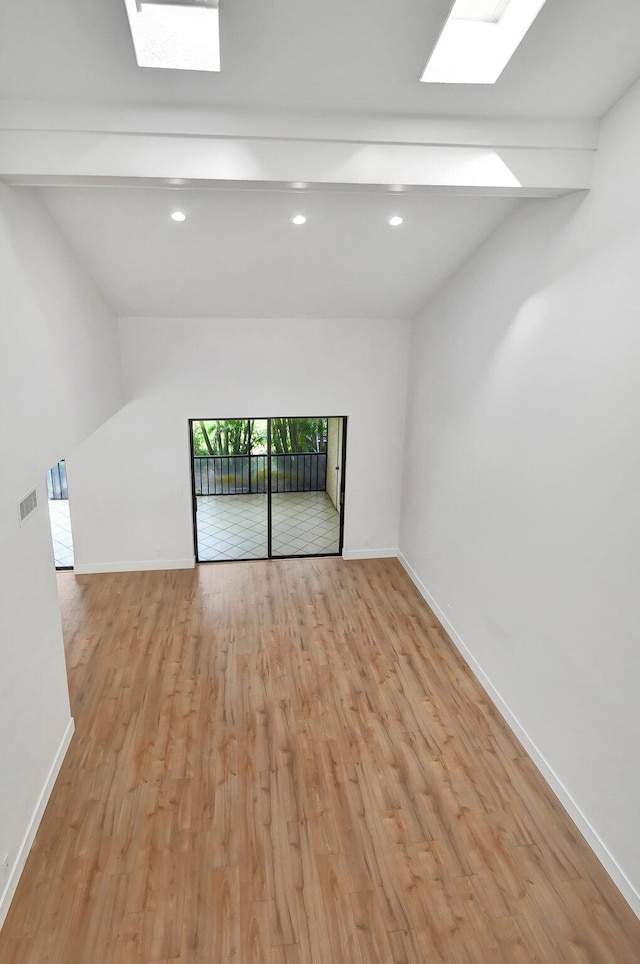 spare room featuring light hardwood / wood-style flooring and lofted ceiling with beams