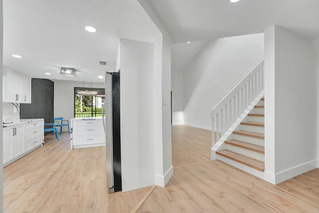 interior space with white cabinets, stainless steel refrigerator, and light wood-type flooring