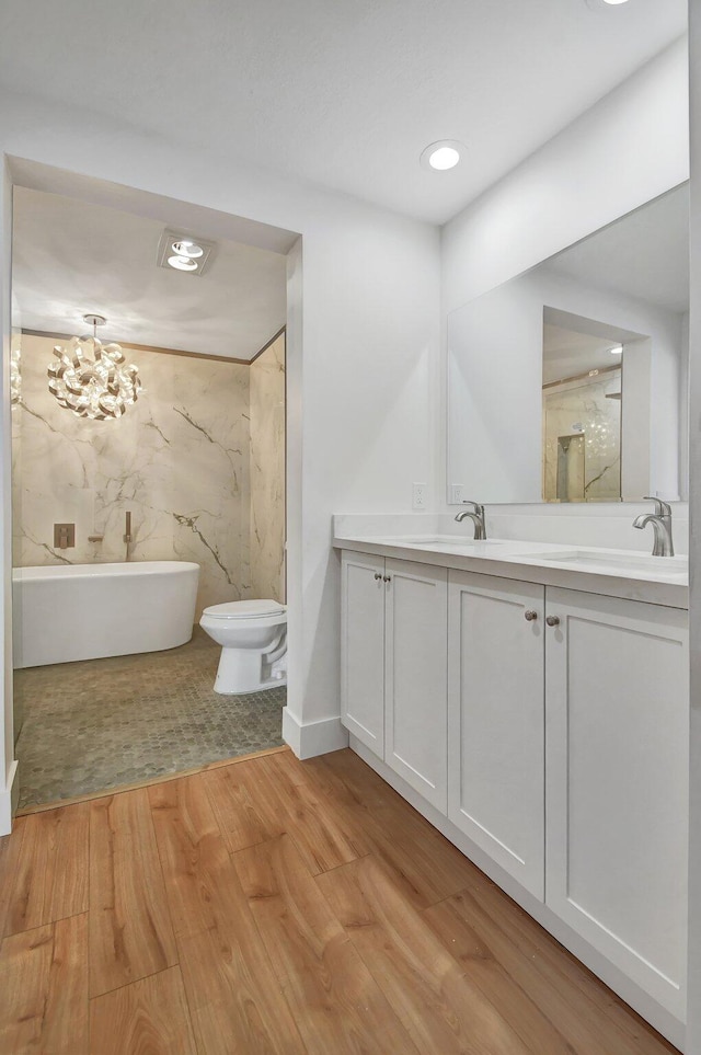 bathroom featuring wood-type flooring, toilet, a washtub, a chandelier, and vanity