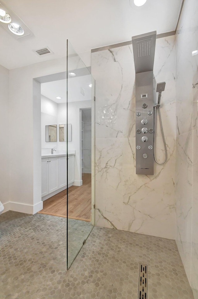 bathroom with hardwood / wood-style flooring, vanity, and a tile shower