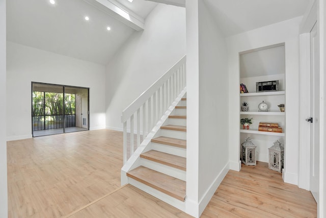 stairway with vaulted ceiling with beams and hardwood / wood-style flooring