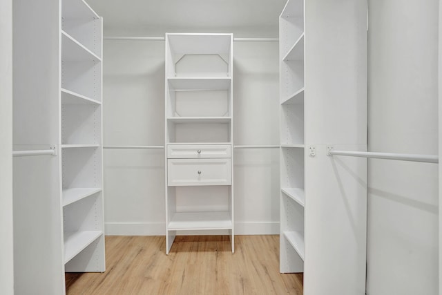 walk in closet with light hardwood / wood-style flooring