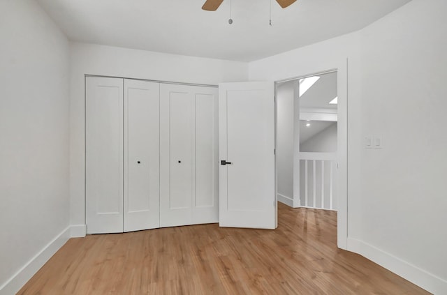 unfurnished bedroom featuring ceiling fan, a closet, and light wood-type flooring