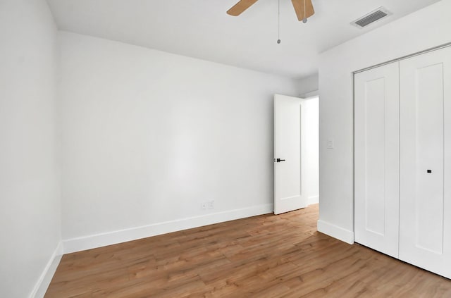 unfurnished bedroom with ceiling fan, a closet, and light wood-type flooring