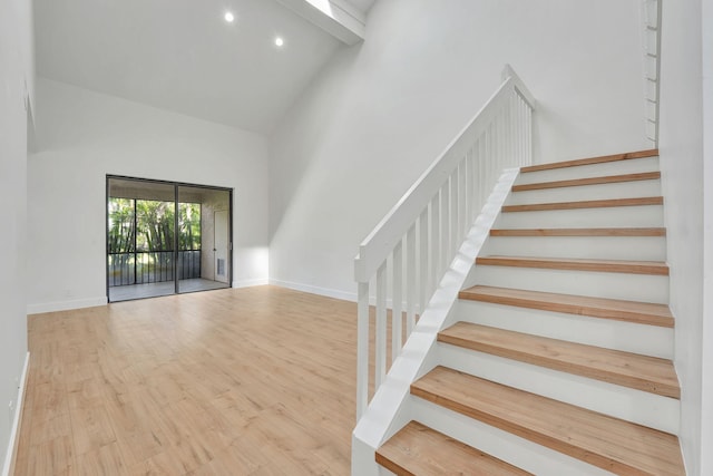 interior space featuring wood-type flooring, beam ceiling, and high vaulted ceiling