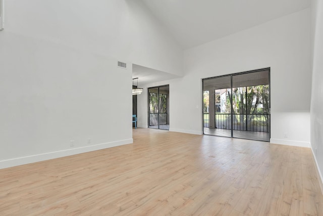 empty room featuring light wood-type flooring and high vaulted ceiling