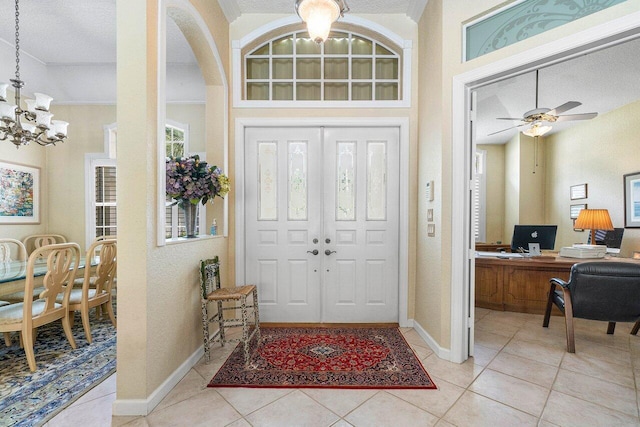 tiled foyer with a textured ceiling and ceiling fan with notable chandelier