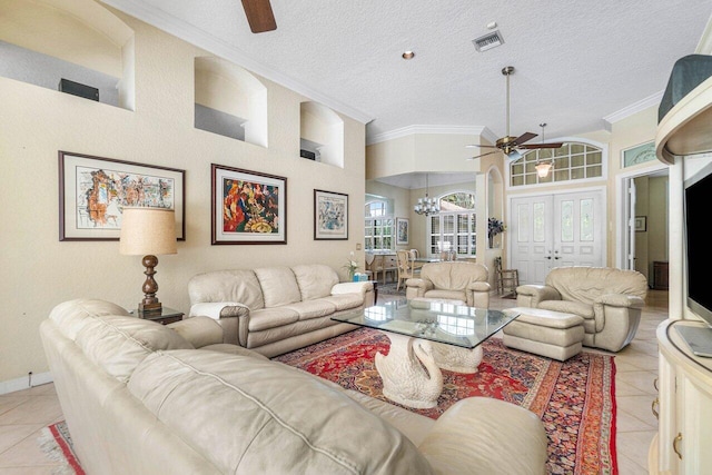 living room featuring ceiling fan with notable chandelier, a textured ceiling, light tile patterned floors, and crown molding