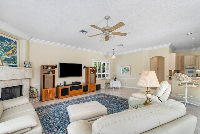 tiled living room with ceiling fan, a textured ceiling, and ornamental molding