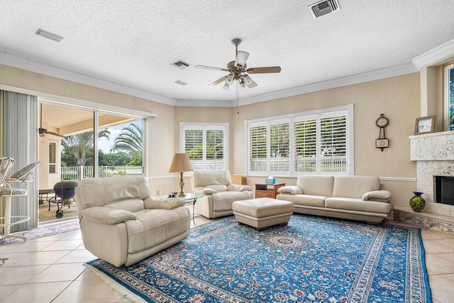 living room with a high end fireplace, a textured ceiling, light tile patterned floors, ornamental molding, and ceiling fan