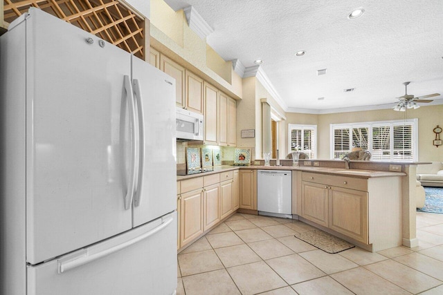 kitchen with light tile patterned floors, ornamental molding, kitchen peninsula, and white appliances