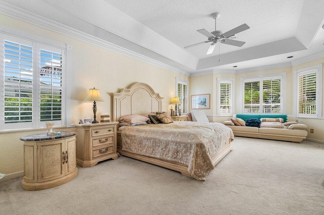 bedroom with a tray ceiling, a textured ceiling, carpet flooring, crown molding, and ceiling fan