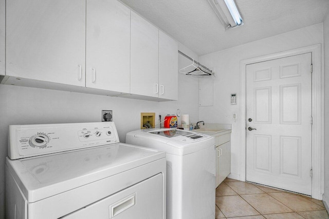 washroom with light tile patterned floors, cabinets, independent washer and dryer, and a textured ceiling