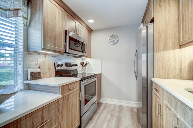 kitchen featuring appliances with stainless steel finishes, light hardwood / wood-style floors, tasteful backsplash, and a healthy amount of sunlight