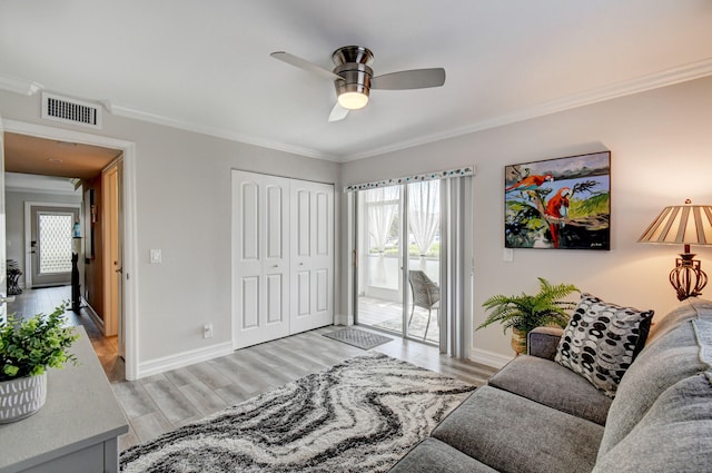 living room featuring ceiling fan, crown molding, and light hardwood / wood-style floors