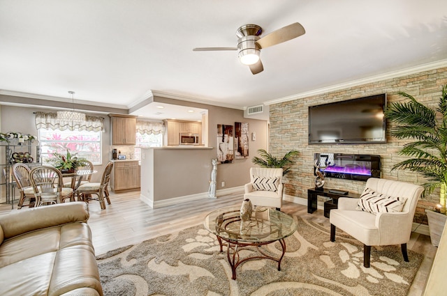 living room with a stone fireplace, ceiling fan with notable chandelier, crown molding, and light hardwood / wood-style floors