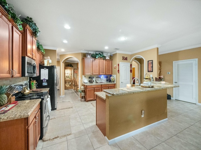 kitchen featuring appliances with stainless steel finishes, an island with sink, decorative backsplash, light tile patterned flooring, and ornamental molding