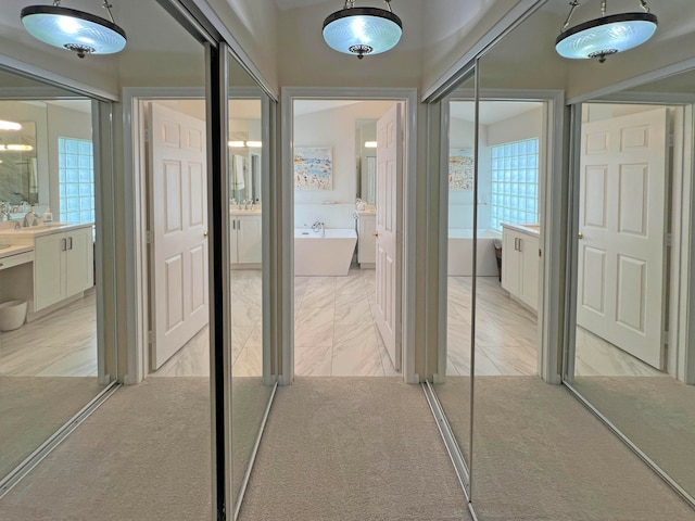 corridor featuring light colored carpet and sink