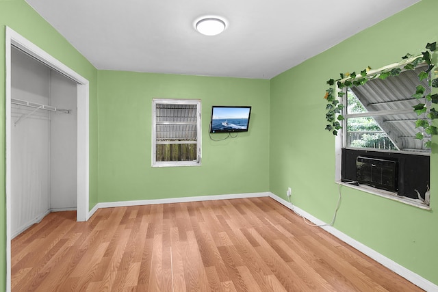 unfurnished bedroom with a closet, cooling unit, and light hardwood / wood-style flooring