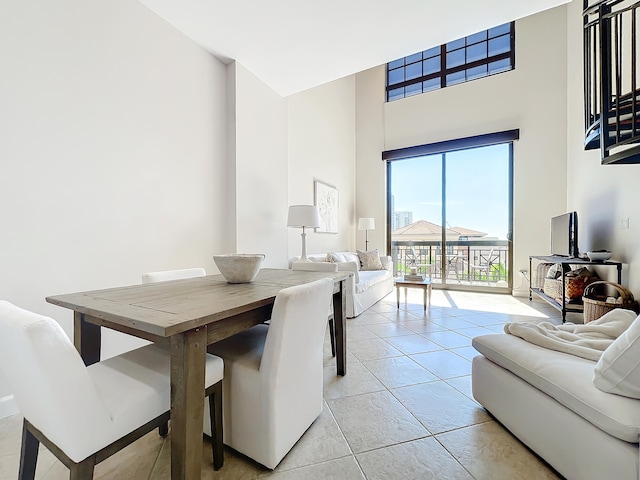 dining space featuring a towering ceiling and light tile patterned flooring