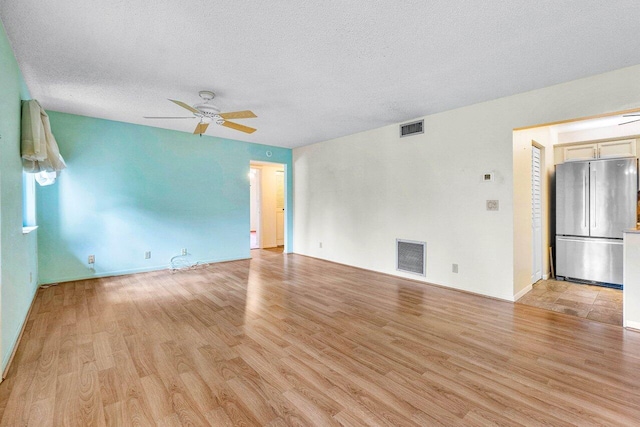 unfurnished room with light hardwood / wood-style flooring, ceiling fan, and a textured ceiling