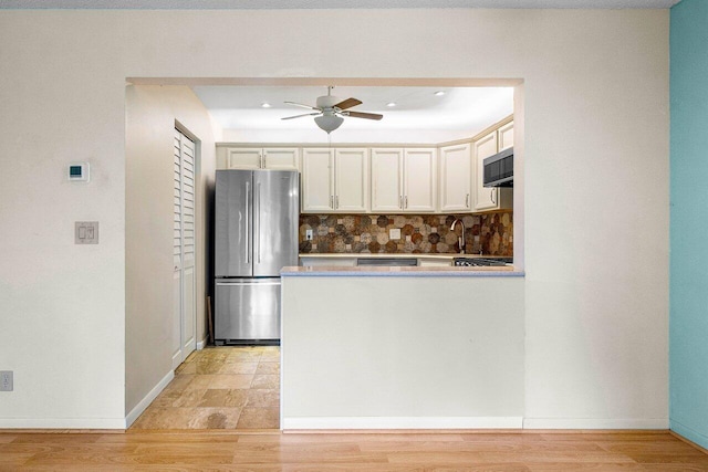 kitchen featuring decorative backsplash, light hardwood / wood-style floors, ceiling fan, and stainless steel appliances