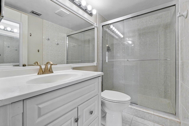 bathroom featuring tile patterned flooring, a shower with shower door, vanity, and toilet